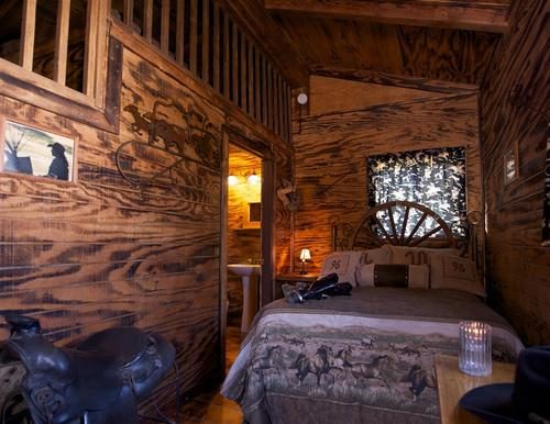 Pine-walled cabin interior with a queen bed and a lamp lit beside the window
